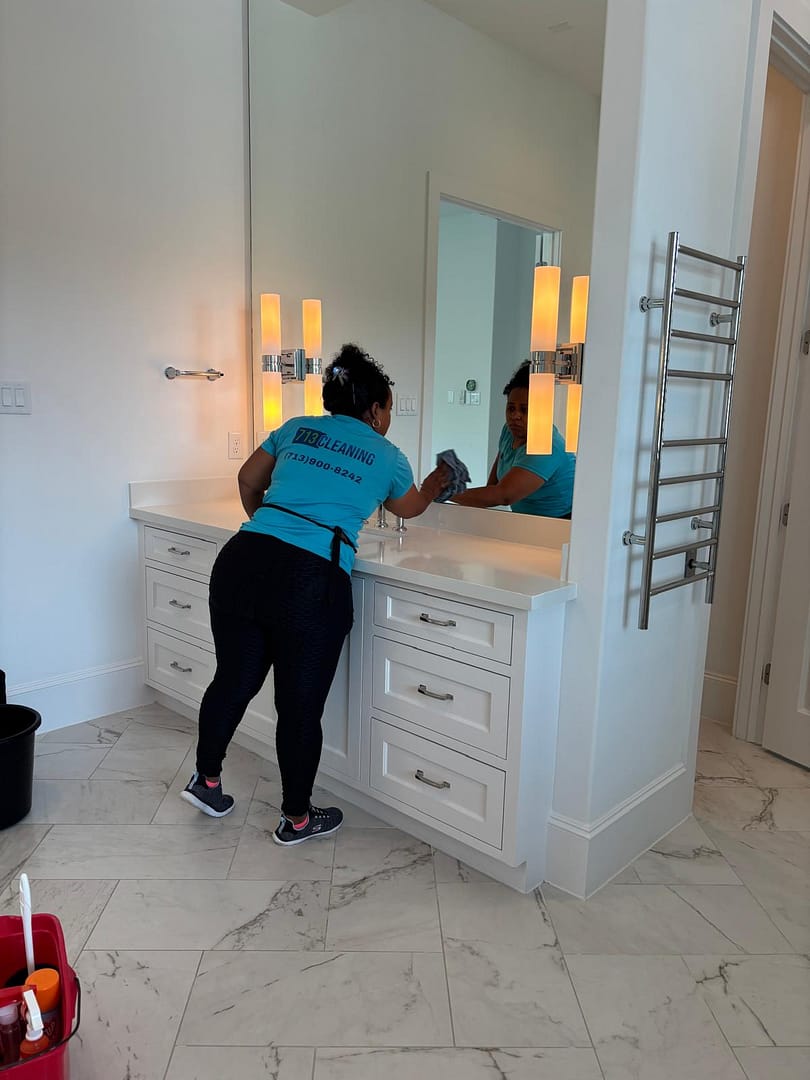 713 Cleaning team member detailing a bathroom vanity and mirror during a deep cleaning in Houston, TX