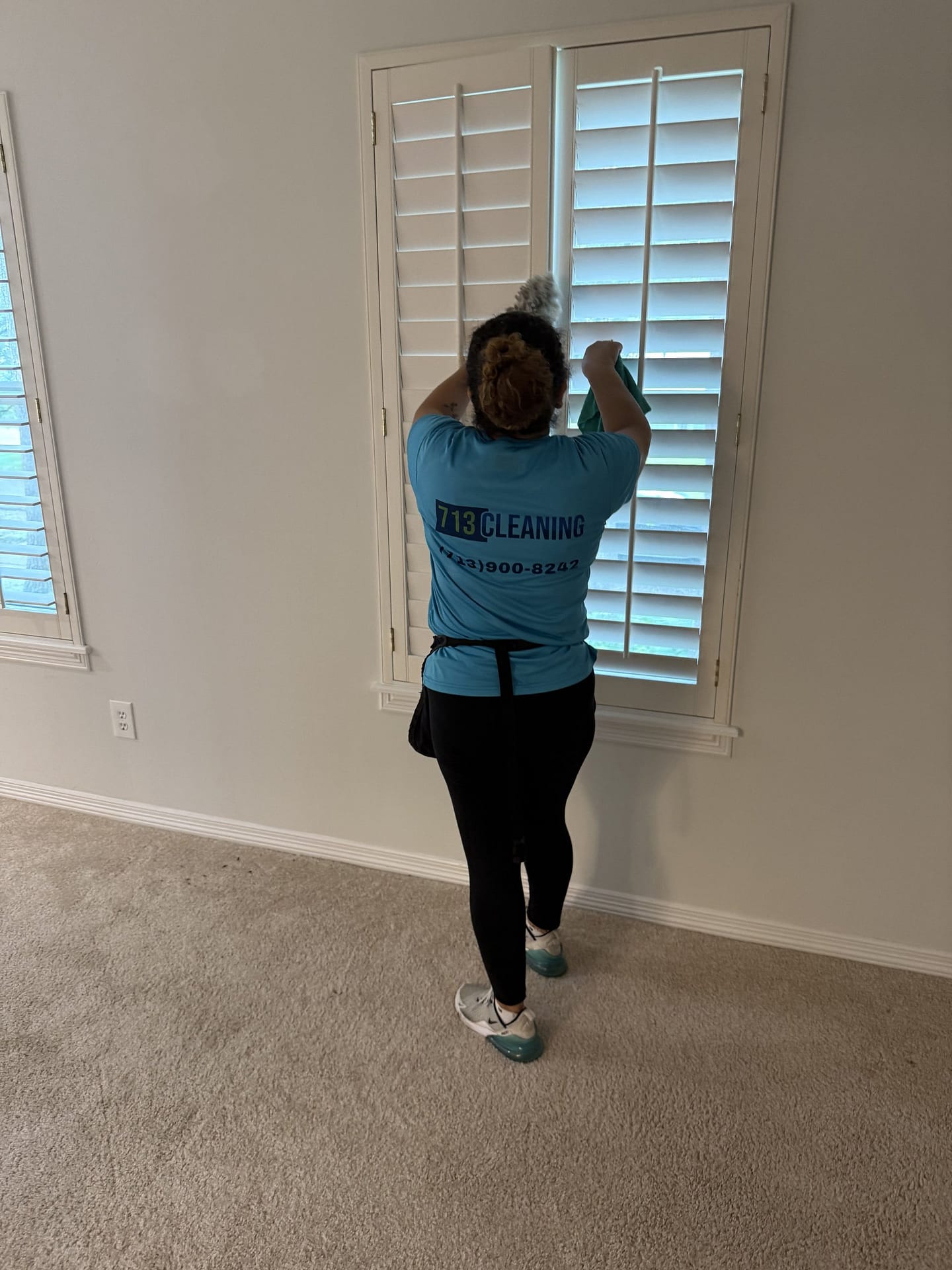 713 Cleaning team member dusting plantation shutter blinds during an allergy season house cleaning in Houston, TX