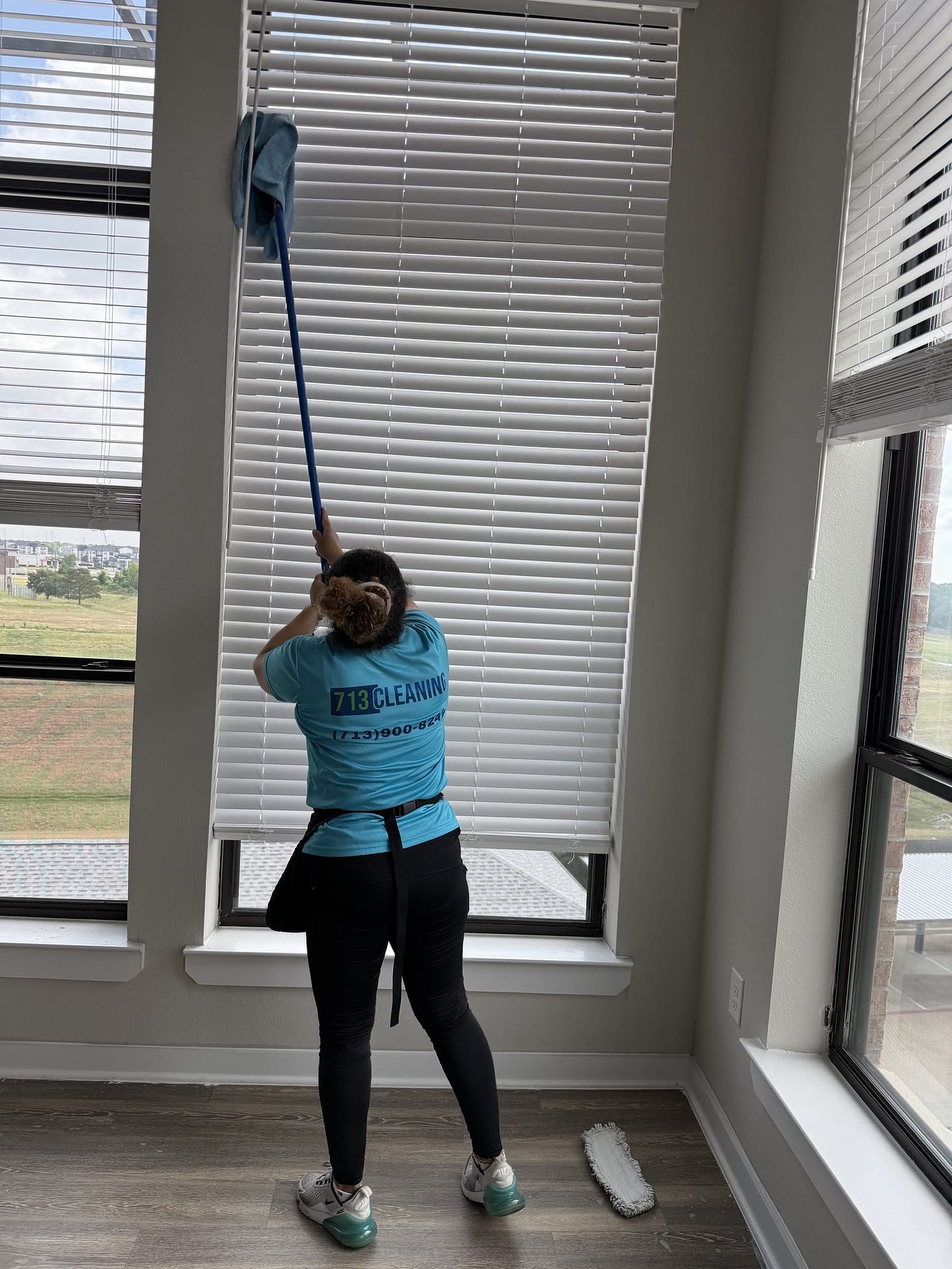 713 Cleaning team member dusting window blinds in a Katy home, with the sills and tracks below, two of the places people forget to clean.