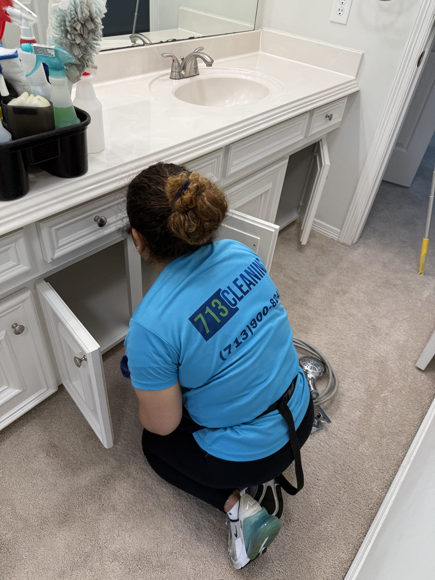 713 Cleaning crew member wiping the inside of an empty bathroom vanity cabinet in a vacant home before the move-out walk-through.